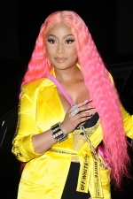 Nicki Minaj flashes her chest under a furry pink jacket as she gives fans
