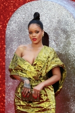 Rihanna spills out of her plunging golden gown as she turns