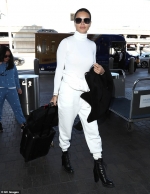 Adriana Lima makes sweats chic as she pairs an all white look with black heeled booties...