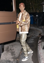 Travis Scott rocks a leopard jacket with two fleece smiley faces on the front