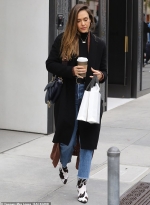 Jessica Alba bundles up in a black duster and jeans with cow print boots